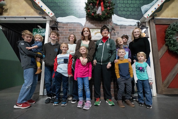 (Francisco Kjolseth | The Salt Lake Tribune) Patti Peterson of Las Vegas is joined by her 12 grandchildren along the walls of the Elf Emporium store front that was built by her family in her honor for the 51st Festival of Trees at the Mountain America Expo Center in Sandy on Tuesday, Nov. 30, 2021. Patti who has terminal cancer and developed a community of friends through her treatments and service to others says, “My cancer journey has been joyful because I wasn’t always thinking about myself.”
