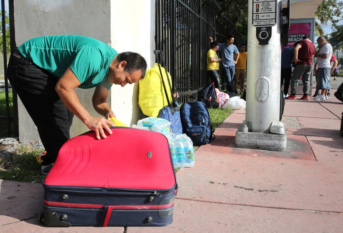 (Marta Lavandier | The Associated Press) Leonel Geronimo, stuffs food into his suitcase as he and others wait for a bus in anticipation of Hurricane Irma in Miami Beach, Fla., Friday, Sept. 8, 2017. Geronimo wants to get to a shelter off the beach, but is not sure what bus to take or which shelter to go.
