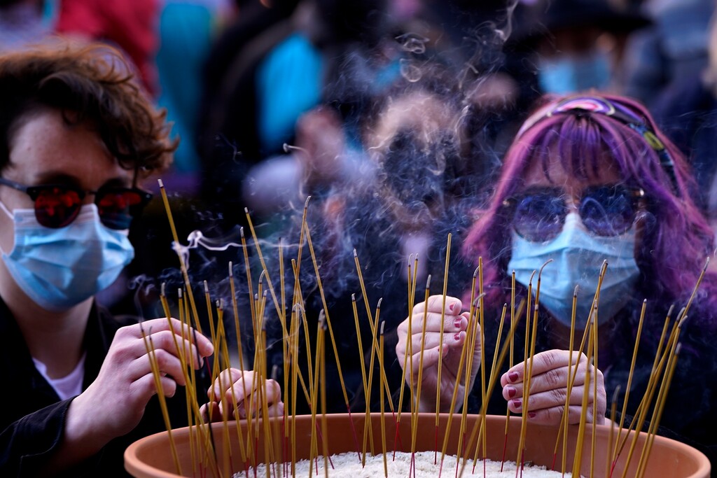People leave incense sticks in a pot of rice to honor the victims of the Atlanta area massage parlors shootings during a memorial in Kansas City, Mo., Sunday, March 28, 2021. The March 17 shootings at three Georgia massage parlors and spas that left eight people dead, six of them women of Asian descent, come on the heels of a recent wave of attacks against Asian Americans since the coronavirus entered the United States. (AP Photo/Charlie Riedel)