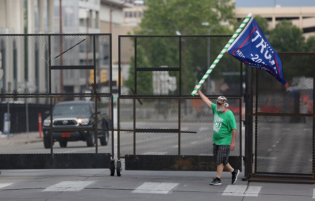 (Mike Simons | Tulsa World via AP) Mike Pellerin waves a Donald Trump campaign flag near a barricade in downtown Tulsa, Okla., ahead of President Donald Trump's Saturday's campaign rally Friday, June 19, 2020.