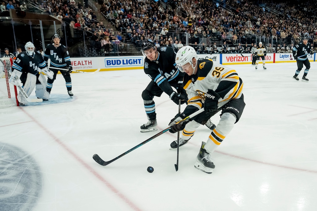 Boston Bruins center Morgan Geekie (39) tries to move the puck under pressure from Utah Hockey Club defenseman Michael Kesselring during the first period of an NHL hockey game, Saturday, Oct. 19, 2024, in Salt Lake City. (AP Photo/Spenser Heaps)
