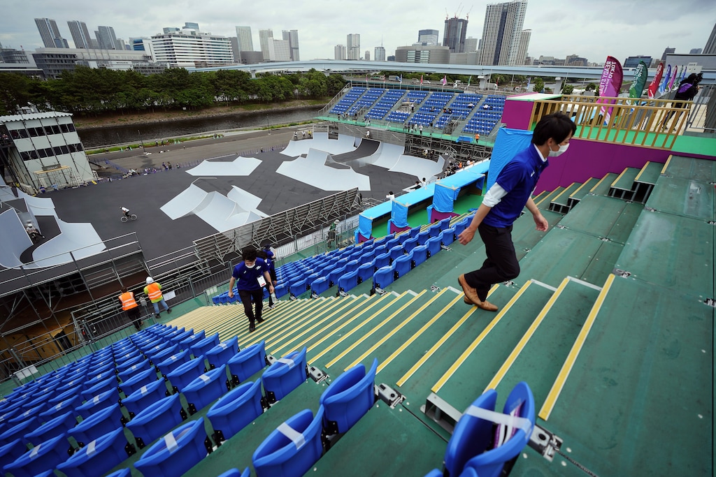 (Eugene Hoshiko | AP) Staffs walk at the grandstand as athletes compete during a Tokyo 2020 Olympic Game Cycling BMX Freestyle test event Monday, May 17, 2021, at the Olympic BMX Course of Ariake Urban Sports Park in Tokyo.