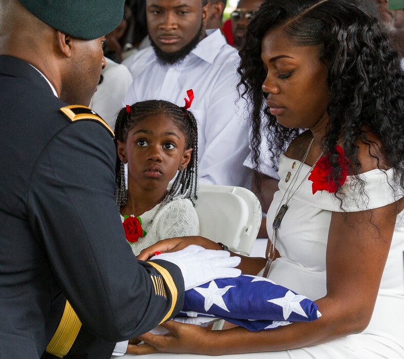 Myeshia Johnson is presented with the U.S. flag that was draped over the casket of her husband, Sgt. La David Johnson, during his burial service at Fred Hunter's Hollywood Memorial Gardens in Hollywood, Fla., on Saturday, Oct. 21, 2017. Mourners remembered not only a U.S. soldier whose combat death in Africa led to a political fight between President Donald Trump and a Florida congresswoman but his three comrades who died with him. (Matias J. Ocner/Miami Herald via AP)