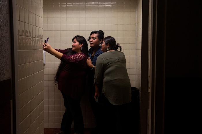 (Adriana Zehbrauskas | The New York Times) Girls take a bathroom selfie during a concert by Stateline, a Navajo country band, in Gallup, N.M., Nov. 6, 2019. At highway honky-tonks, casino lounges and far-flung dance halls, a form of music that many associate with rural white America is flourishing in the heart of Indian country, and no tribe have put their own stamp on country music quite like the Navajo.