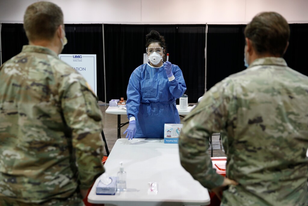 (John Locher | AP) Diana Vega, a registered respiratory therapist, instructs Nevada National Guardsmen on how to test people during the setup of a temporary coronavirus testing site Monday, Aug. 3, 2020, in Las Vegas.