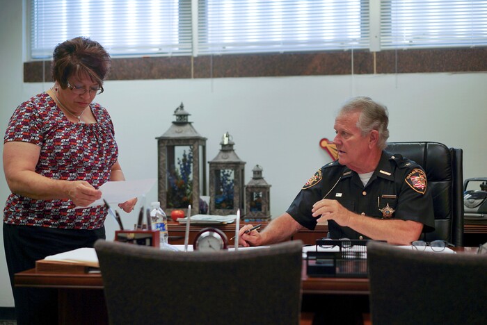 In this Aug. 9, 2017, photo, Lucas County Sheriff John Tharp speaks with his assistant Sandy Heban in his office in Toledo, Ohio. Police and rescue crews say drivers overdosing on heroin and other drugs are driving up the number of car crashes. Tharp says drivers in his county overdose on opioids so powerful it requires multiple doses of opiate antidote naloxone in order to revive them. (AP Photo/Dake Kang)