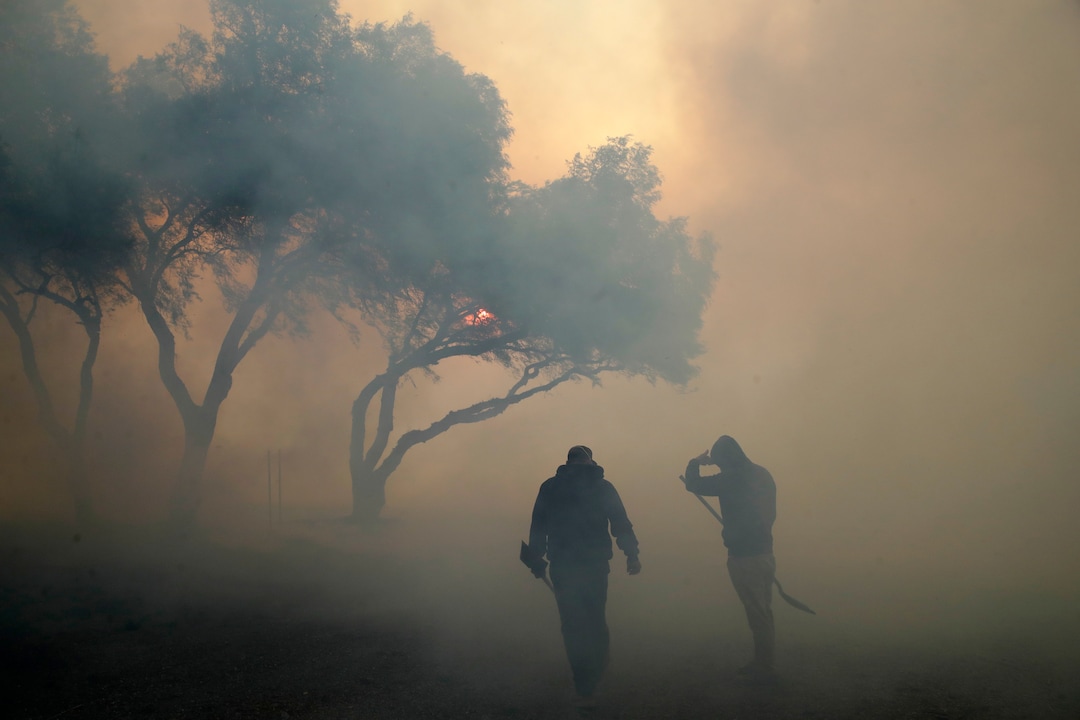 (Marcio Jose Sanchez | AP)  Dean Cato, left, and his son Robert use shovels to try to put out hotspots caused by the Easy fire at American Soil and Nursery Wednesday, Oct. 30, 2019, in Simi Valley, Calif.  A new wildfire erupted Wednesday in wind-whipped Southern California, forcing the evacuation of the Ronald Reagan Presidential Library and nearby homes, as both ends of the state struggled with blazes, dangerously gusty weather and deliberate blackouts.