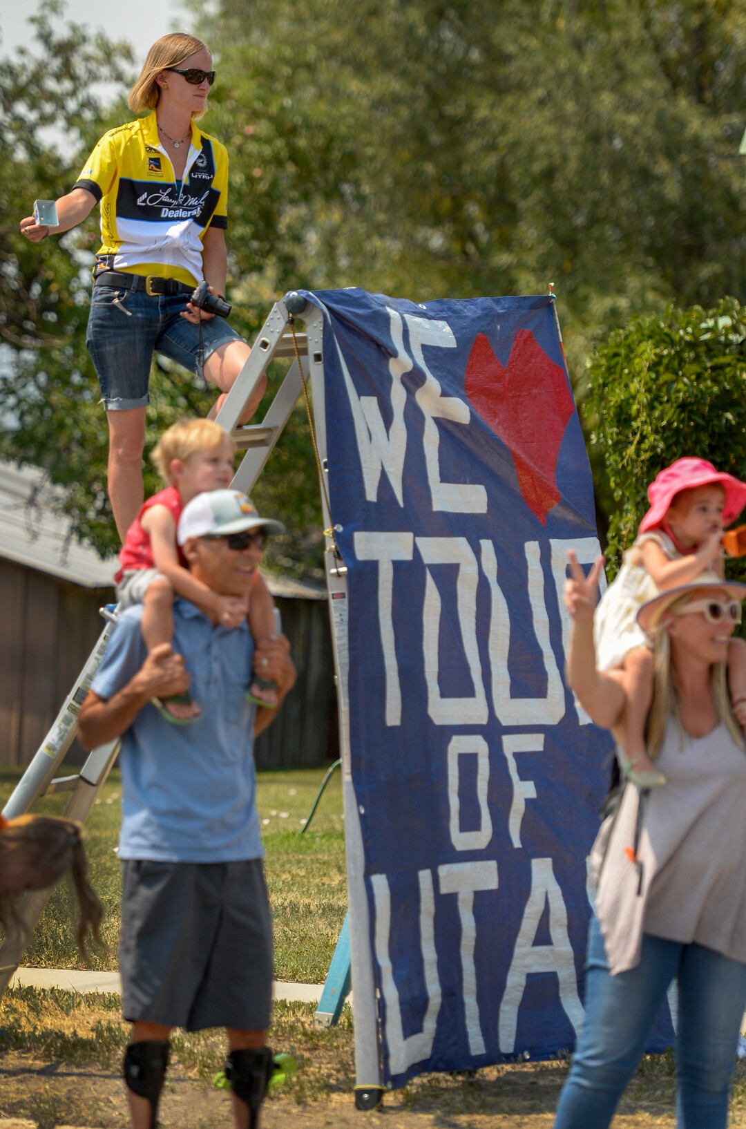 Leah Hogsten  |  The Salt Lake Tribune   Katie Stellpflug stands on a ladder in Kamas next to the sign she made for the Tour of Utah's Stage 6, Sunday, August 12, 2018.  .  