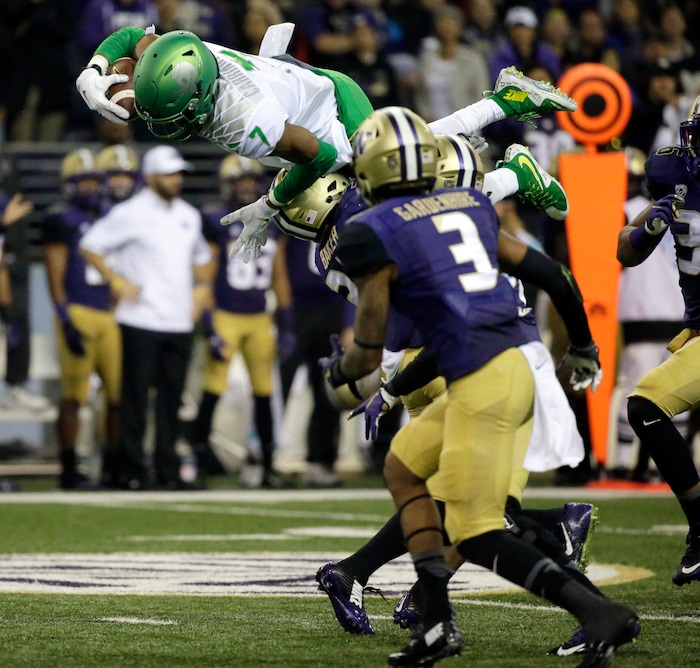 Oregon wide receiver Darren Carrington (7) leaps over Washington defensive back Budda Baker as Washington's Darren Gardenhire (3) watches during the second half of an NCAA college football game, Saturday, Oct. 17, 2015, in Seattle. Oregon won 26-20. (AP Photo/Ted S. Warren)