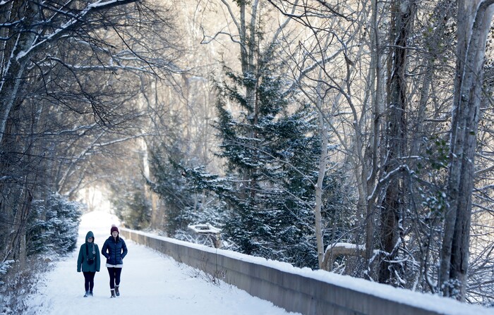 Brooke Meadows, left, and Alex Ondrus go for a walk in Radnor Lake State Park, Tuesday, Jan. 16, 2018, in Nashville, Tenn. A winter storm brought snow and cold temperatures to the area, causing the closing of schools and businesses. (AP Photo/Mark Humphrey)