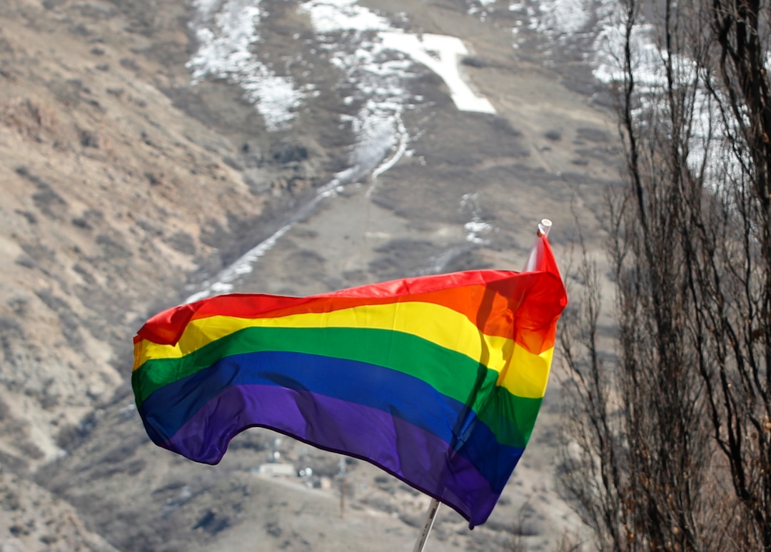 (George Frey  |  special to The Salt Lake Tribune) A gay pride flag flies in front of the ÒYÓ as BYU students and others gather in front of the Ernest L. Wilkinson Student Center on the campus of Brigham Young University to protest BYUÕs rollback of a newly announced policy change on LGBTQ students on March 5, 2020 in Provo, Utah.