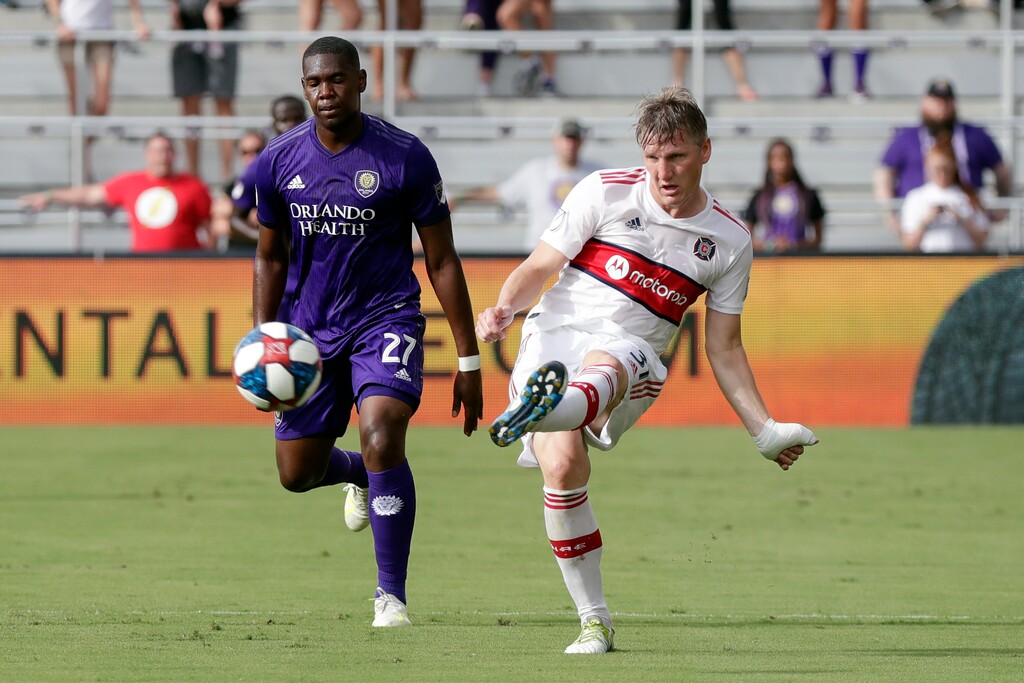 Chicago Fire's Bastian Schweinsteiger, right, passes the ball in front of Orlando City's Kamal Miller (27) during the first half of an MLS soccer match, Sunday, Oct. 6, 2019, in Orlando, Fla. (AP Photo/John Raoux)