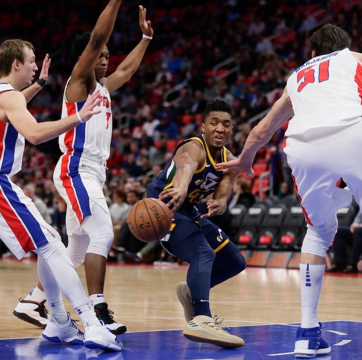 Utah Jazz guard Donovan Mitchell (45) passes the ball against Detroit Pistons guard Luke Kennard, left, forward Stanley Johnson and center Boban Marjanovic (51) during the first half of an NBA basketball game Wednesday, Jan. 24, 2018, in Detroit. (AP Photo/Duane Burleson)