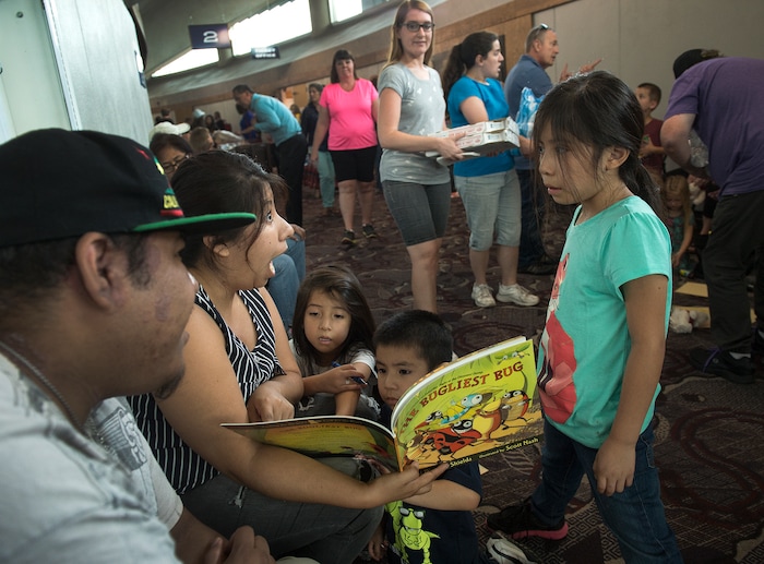 (Leah Hogsten  |  The Salt Lake Tribune) Uintah Fire evacuees l-r Eddie Guzman, his sister Susie Alvarez and her children Isabella, Matthew and Abigail read a children's book in the hallway of  the Dee Events Center on the Weber State University campus in Ogden.  The Uintah Fire is still burning through the town of Uintah and pockets of South Weber, as well as the unincorporated subdivision of Uintah Highlands.
