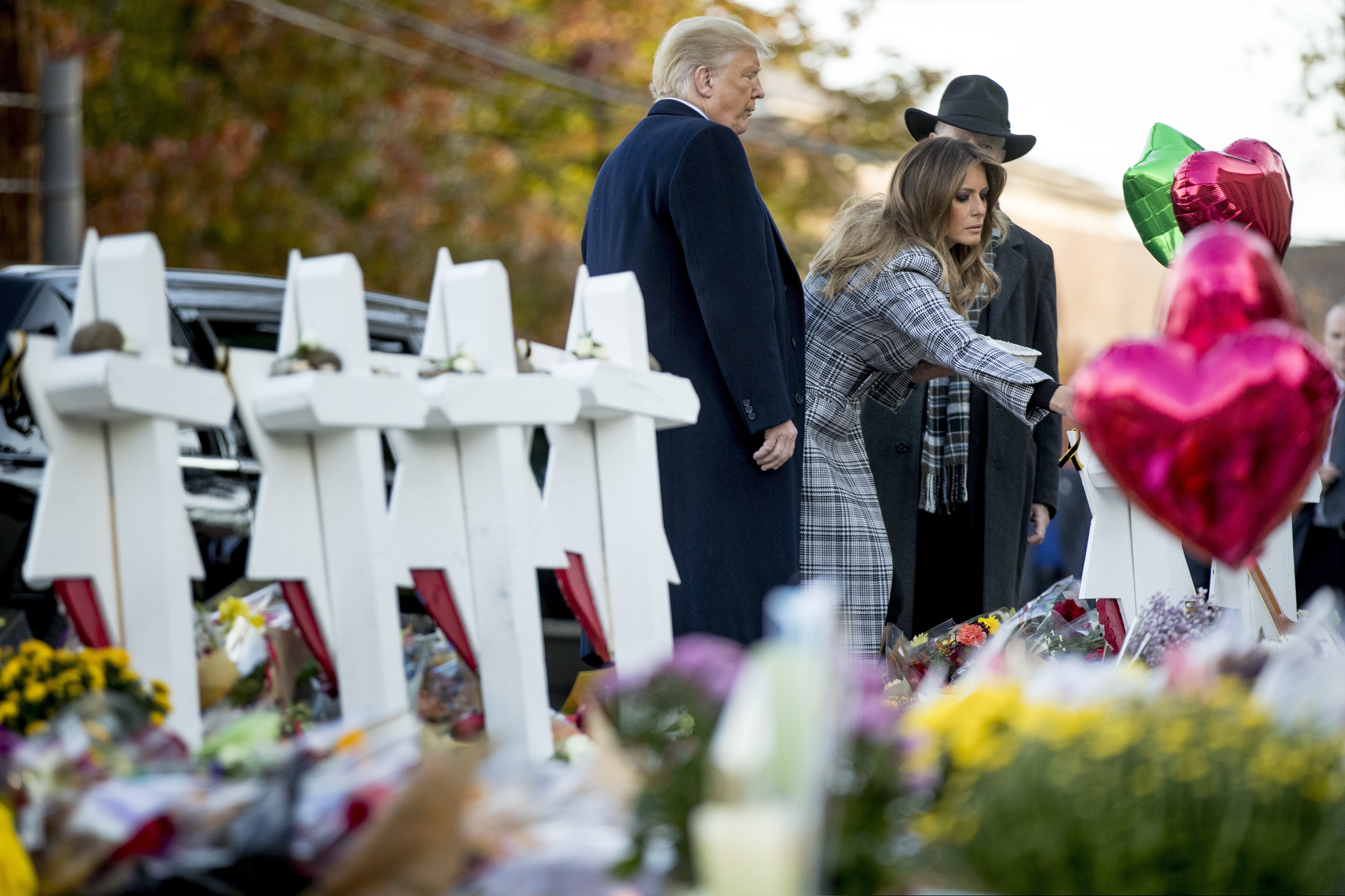 First lady Melania Trump, accompanied by President Donald Trump, and Tree of Life Rabbi Jeffrey Myers, right, places a white flower at a memorial for those killed at the Tree of Life Synagogue in Pittsburgh, Tuesday, Oct. 30, 2018. (AP Photo/Andrew Harnik)