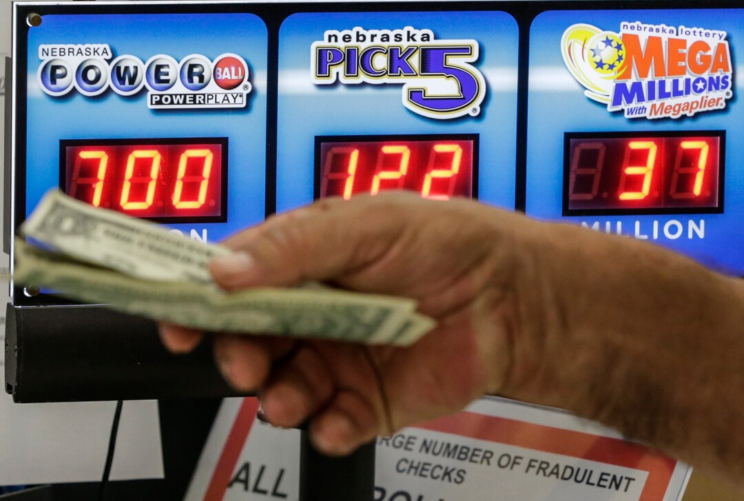 A customer hands over money for a Powerball ticket in Omaha, Neb., Wednesday, Aug. 23, 2017. Lottery officials said the grand prize for Wednesday night's drawing has reached $700 million, the second -largest on record for any U.S. lottery game. (AP Photo/Nati Harnik)