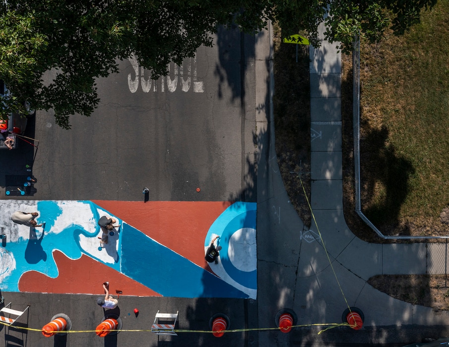 (Leah Hogsten | The Salt Lake Tribune) Volunteers paint a traffic-calming street mural near Parkview Elementary School on Emery Street, Saturday, July 29, 2023. The abstract mural is one of three paintings inspired by the desert, Wasatch Mountains and the Jordan River.