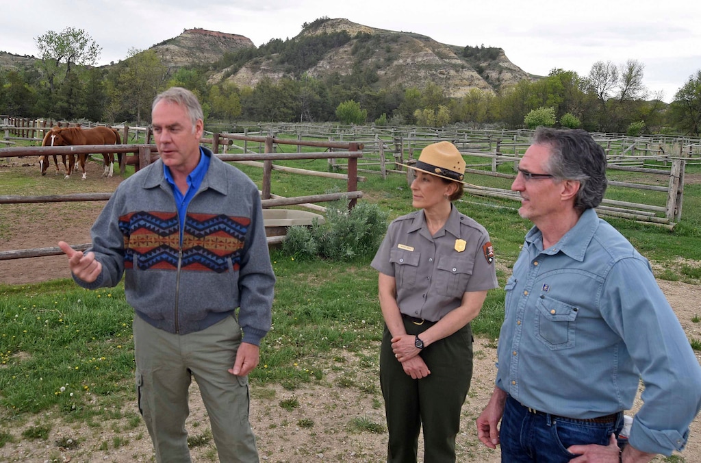 Secretary of the Interior Ryan Zinke, left, speaks at Peaceful Valley Ranch in Theodore Roosevelt National Park on Tuesday, May 22, 2018, while touring the area with park superintendent Wendy Ross, center, and North Dakota Gov. Doug Burgum, right. Peaceful Valley is near Medora and dates to 1885 and overlooks the Little Missouri River and Badlands of western North Dakota. (Tom Stromme/The Bismarck Tribune via AP)