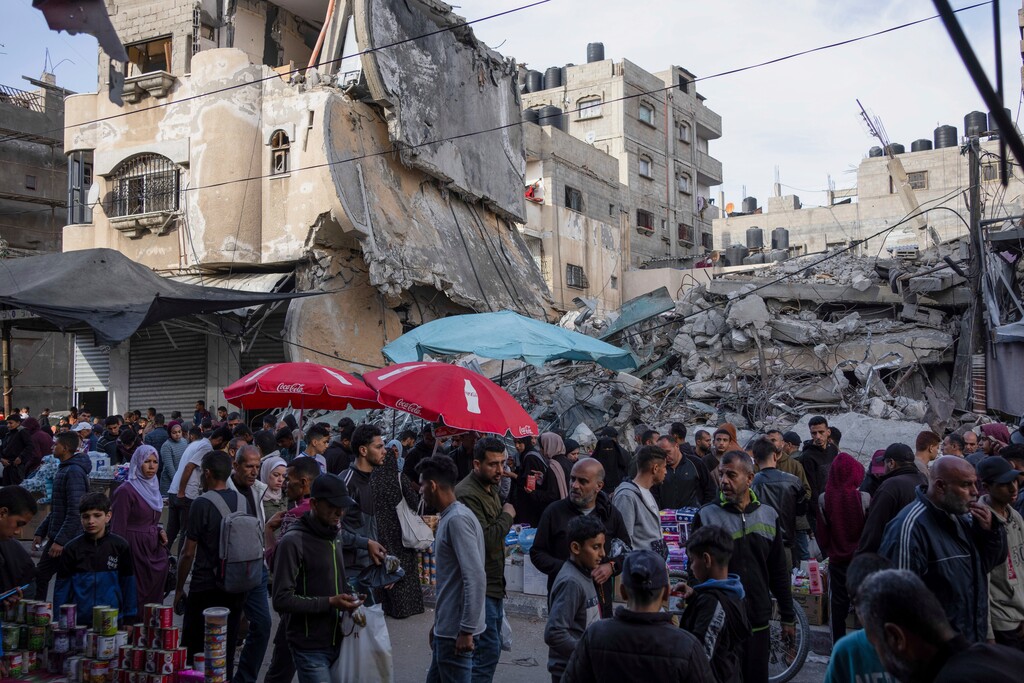 (Fatima Shbair | The Associated Press) Palestinians buy food at a local market next to a destroyed residential building by the Israeli airstrikes, during the Muslim holy month of Ramadan, in Rafah, Gaza Strip, Thursday, March 14, 2024.