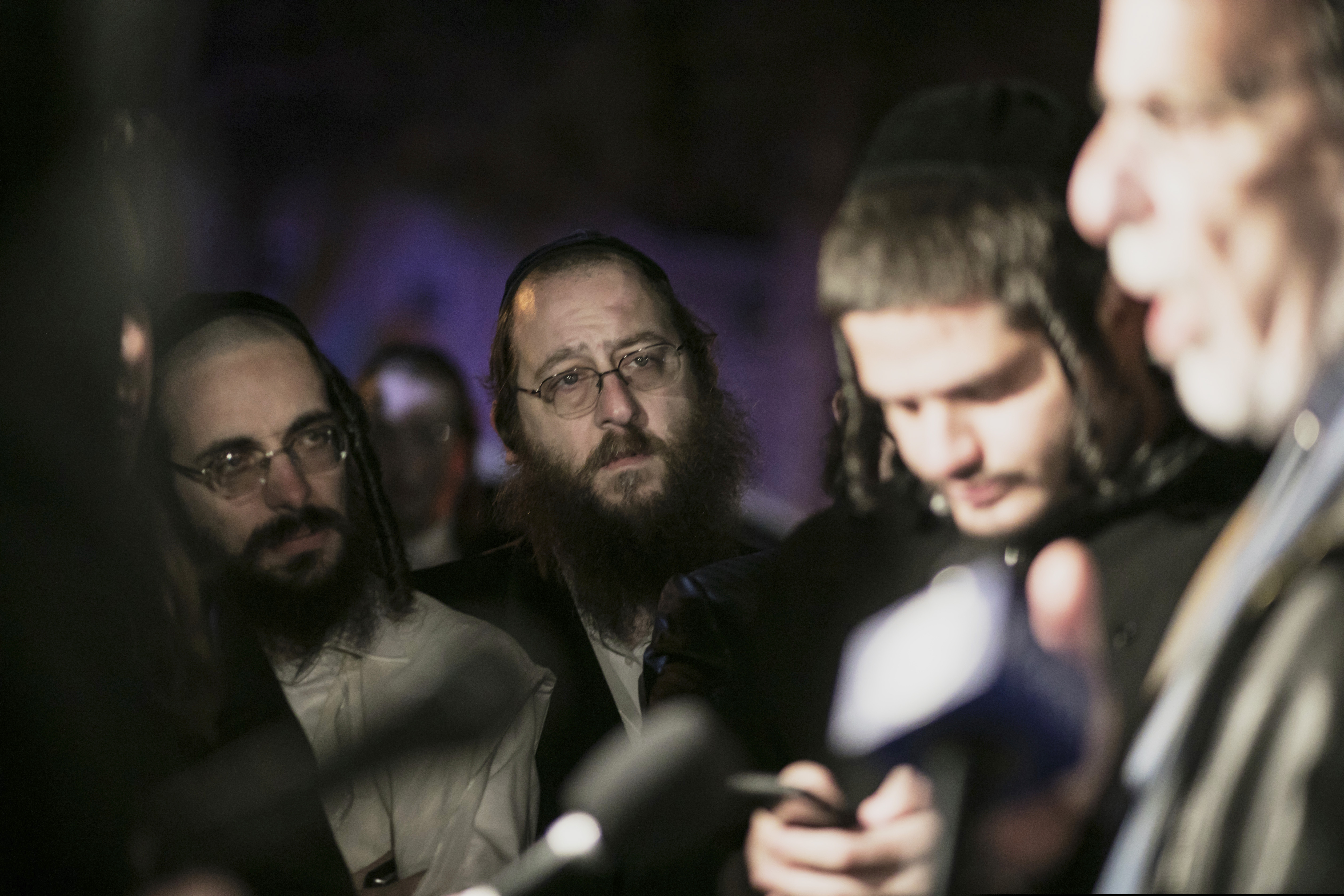 (Allyse Pulliam | AP) Orthodox Jewish people listen to N.Y. state Assemblyman Dov Hikind speak in Monsey, N.Y., Sunday, Dec. 29, 2019, following a stabbing late Saturday during a Hanukkah celebration. A man attacked the celebration at a rabbi's home north of New York City late Saturday, stabbing and wounding several people before fleeing in a vehicle, police said.