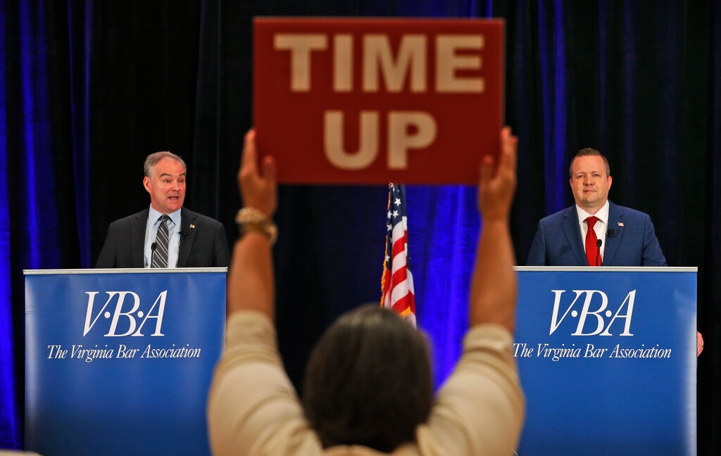 A time keeper holds a sign as U.S. Sen. Tim Kaine, left, and Republican challenger Corey Stewart, right, debate during the Virginia Bar Association debate at the Homestead in Hot Springs , Va., Saturday, July 21, 2018. (AP Photo/Steve Helber)