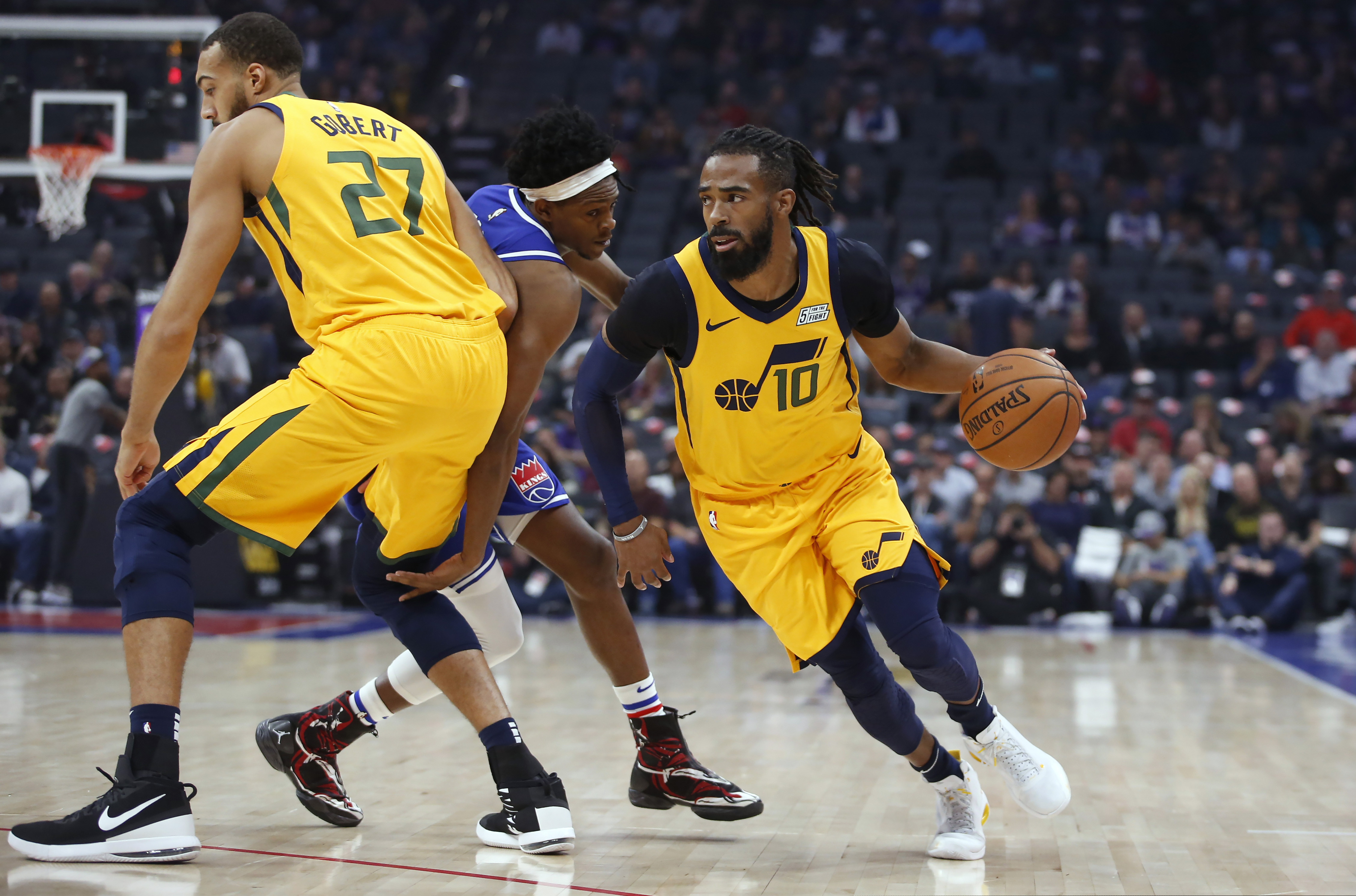 Utah Jazz guard Mike Conley, right, uses a screen set by Rudy Gobert, left, to elude Sacramento Kings guard De'Aaron Fox, center, during the first quarter of an NBA basketball game in Sacramento, Calif., Friday, Nov. 1, 2019. (AP Photo/Rich Pedroncelli)