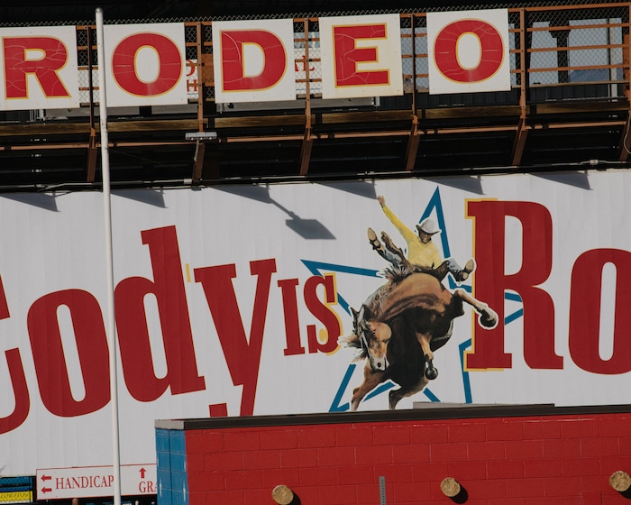 (Elliot Ross | The New York Times) Signage adorns the side of Cody Stampede Rodeo Grounds, declaring the rodeo heritage of Cody, Wyo., Jan. 28, 2020. Cody is near Yellowstone National Park, and so its biggest industry is tourism; on summer weekends, its population can grow by about 50 percent, with visitors stopping in to see the rodeo and the nightly recreations of Old West gunfights before heading west to the park.