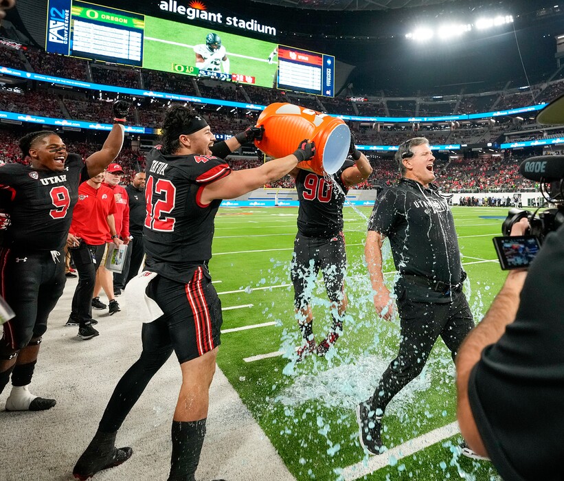 (Leah Hogsten | The Salt Lake Tribune) Utah Utes defensive tackle Devin Kaufusi (90) and Utah Utes defensive end Mika Tafua (42) drench Utah Utes head coach Kyle Whittingham. The Utes defeated the Oregon Ducks to win the 2021 Pac12 Football Championship title at Allegiant Stadium in Las Vegas, Dec 3, 2021.
