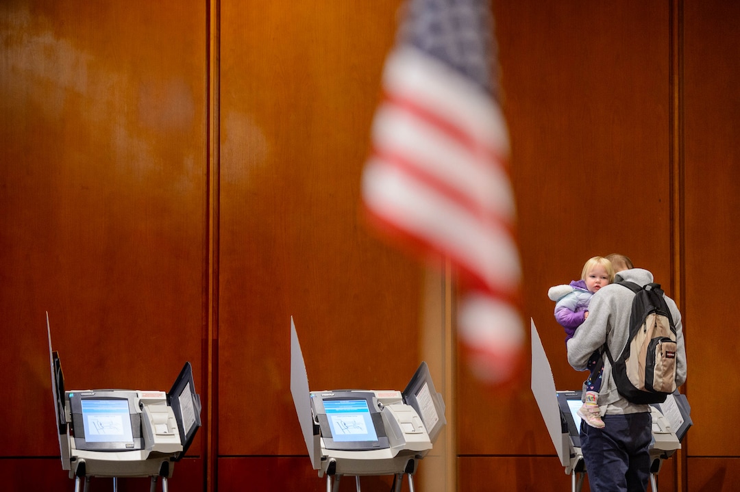 (Trent Nelson  |  Tribune file photo) This March 3, 2020, file photo shows Isla Siegel in the arms of her father Scott, as he votes at the University of Utah's Marriott Library in Salt Lake City.