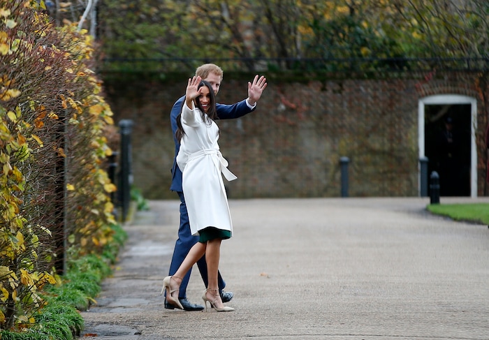 Britain's Prince Harry and Meghan Markle wave after posing for the media in the grounds of Kensington Palace in London, Monday Nov. 27, 2017. It was announced Monday that Prince Harry, fifth in line for the British throne, will marry American actress Meghan Markle in the spring, confirming months of rumors. (AP Photo/Alastair Grant)