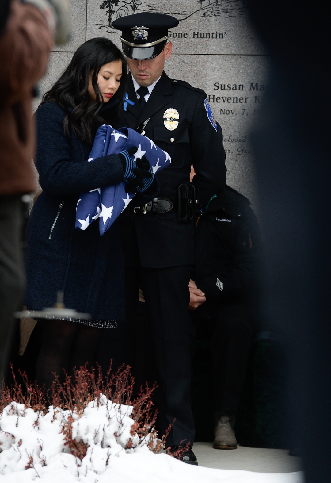 (Francisco Kjolseth  |  The Salt Lake Tribune)  Elizabeth Romrell is accompanied by South Salt Lake officer Lewis Lombardo as she holds the flags she was presented by the Marine Corps and South Salt Lake police department during funeral services for her husband, police officer David Romrell, at Larkin Sunset Gardens Cemetery in Sandy, Wed. Dec. 5, 2018.