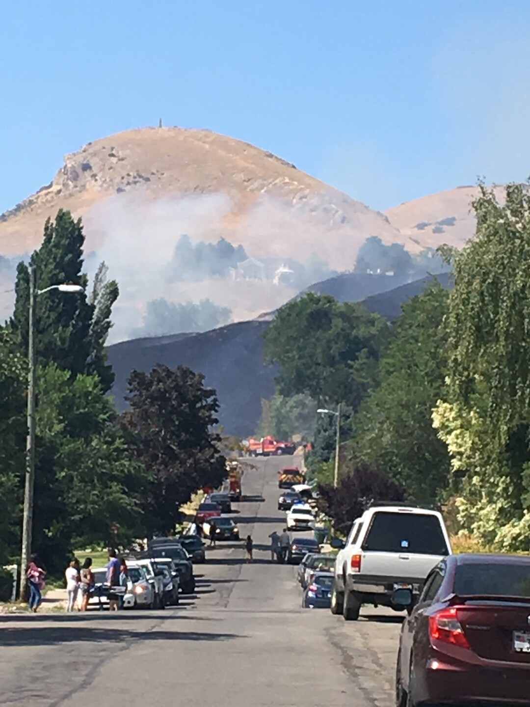 (James Semerad | For The Tribune) Columbus Street passersby watch as hills to the north are scarred by a fire near the Utah Capitol on Tuesday, July 24, 2018.
