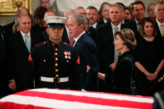 Former President George W. Bush, with his wife former first lady Laura, walks past the casket of his father, former President George H.W. Bush at the Capitol in Washington, Monday, Dec. 3, 2018. (Jonathan Ernst/Pool Photo via AP)