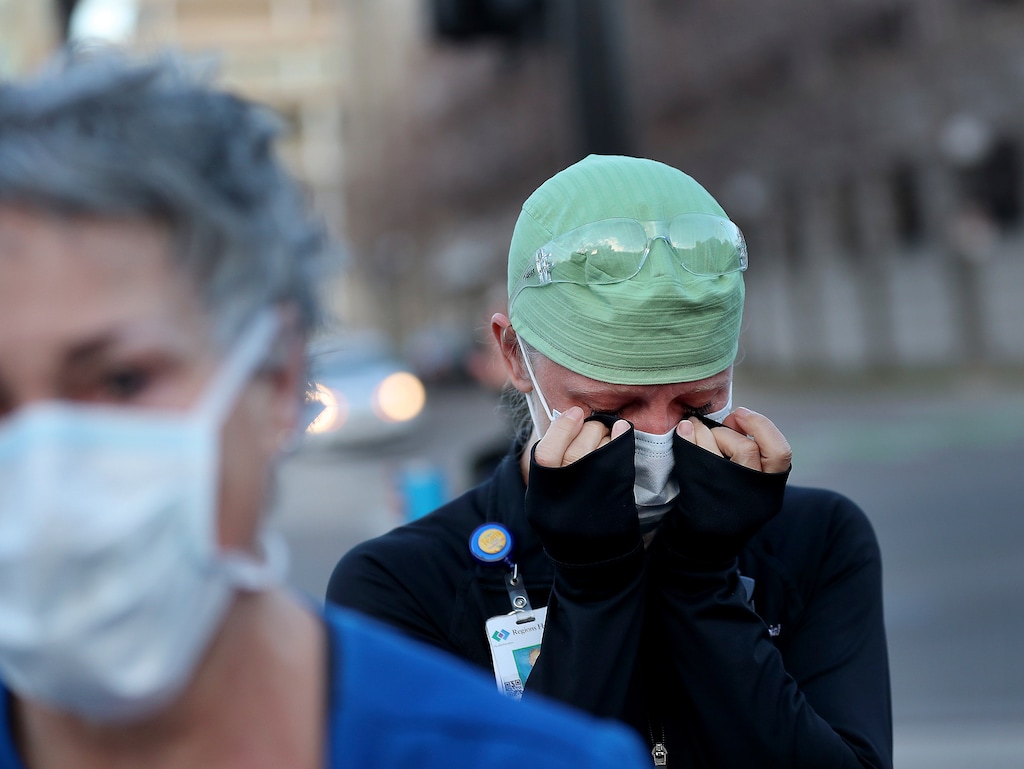 Healthcare workers at Regions Hospital, including Tamara Hill, an ER nurse, seen wiping away tears, come outside to thank Xcel Energy crew members who had lined the street outside Regions to greet healthcare workers Wednesday, April 22, 2020, in St. Paul, Minn., during the coronavirus outbreak. (David Joles/Star Tribune via AP)