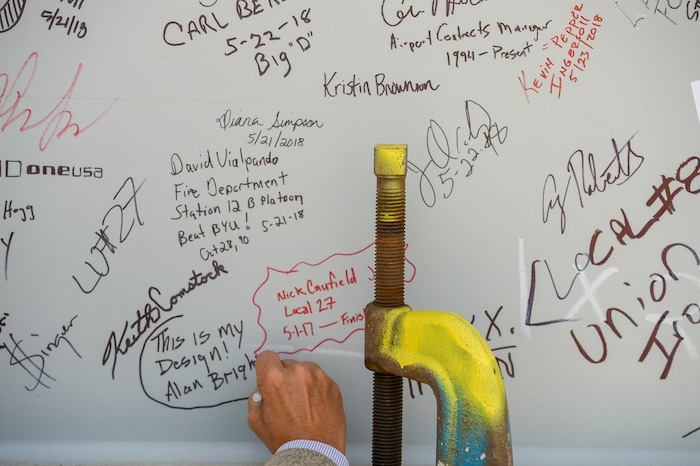 (Leah Hogsten  |  The Salt Lake Tribune) Alan Bright, Design Principal for HOK and the design architect for Salt Lake City International Airport's new terminal signs his name to the beam during Wednesday's "topping out" ceremony to raise the last steel beams to a high point on the new terminal building, Wednesday, May 23, 2018. The new $485 million terminal building will cover 866,087 square feet and used 11,000 tons of structural steel and 22 miles of steel piles.