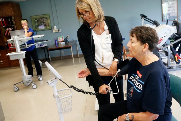In this Aug. 15, 2017, photo, therapist Maureen Devereaux, second from right, takes Rita Driscoll's blood pressure before Driscoll walks on a treadmill at University of Minnesota Medical Center in Minneapolis. After years of leg pain slowing her down, Driscoll learned she has peripheral artery disease, or PAD. Medicare soon will start paying hospitals and clinics for these exercise sessions, making the therapy available for thousands of older Americans with a specific type of leg pain. (AP Photo/Jim Mone)