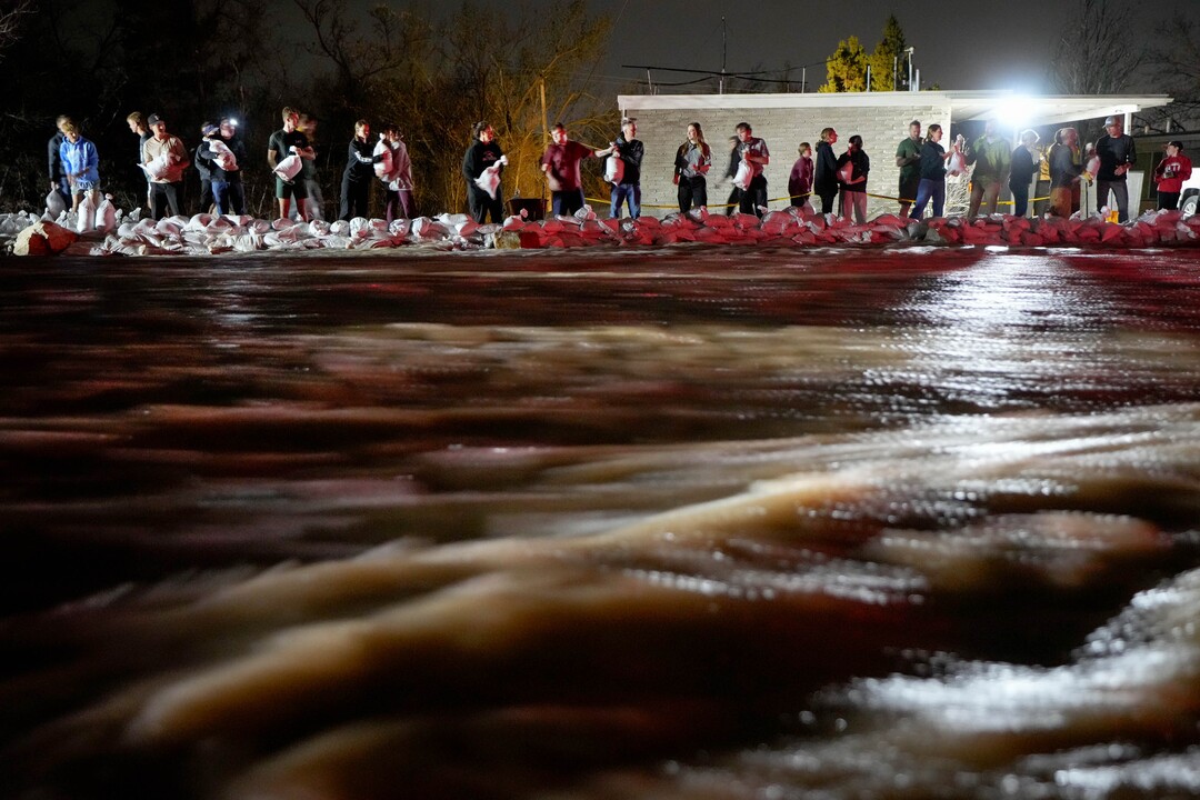 (Francisco Kjolseth | The Salt Lake Tribune) People work to protect homes into the night along 1700 South in Salt Lake City from the rising flow of Emigration Creek through Wasatch Hollow Park on Wednesday, April 12, 2023. 