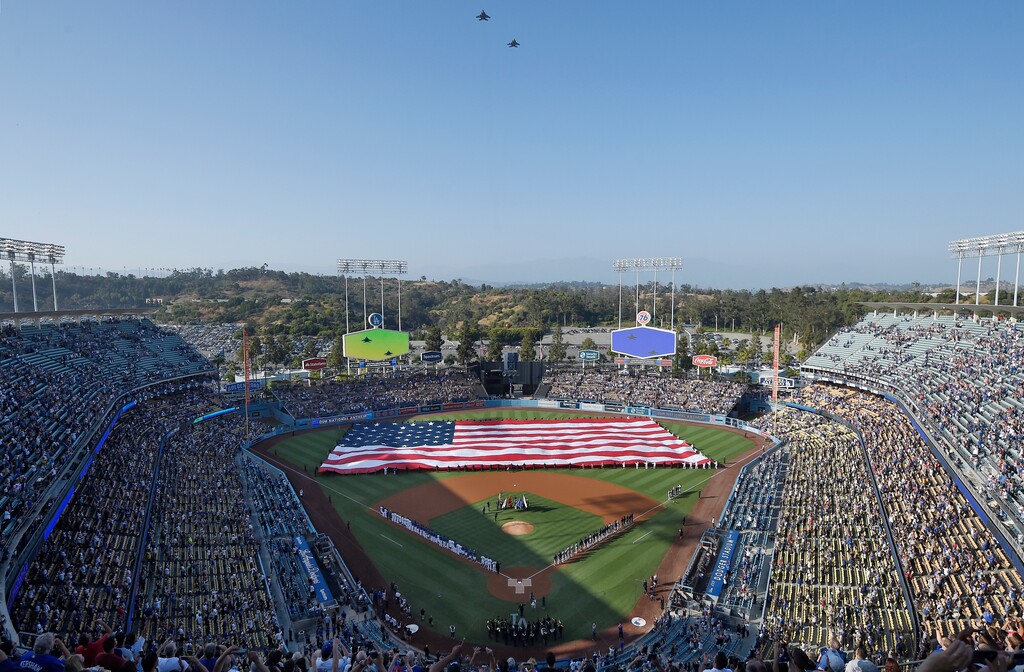 (Mark J. Terrill | AP) A U.S. flag covers the outfield during the national anthem as F-15 Eagle fighter aircraft fly over prior to a baseball game between the Los Angeles Dodgers and the San Diego Padres on Thursday, July 4, 2019, in Los Angeles.