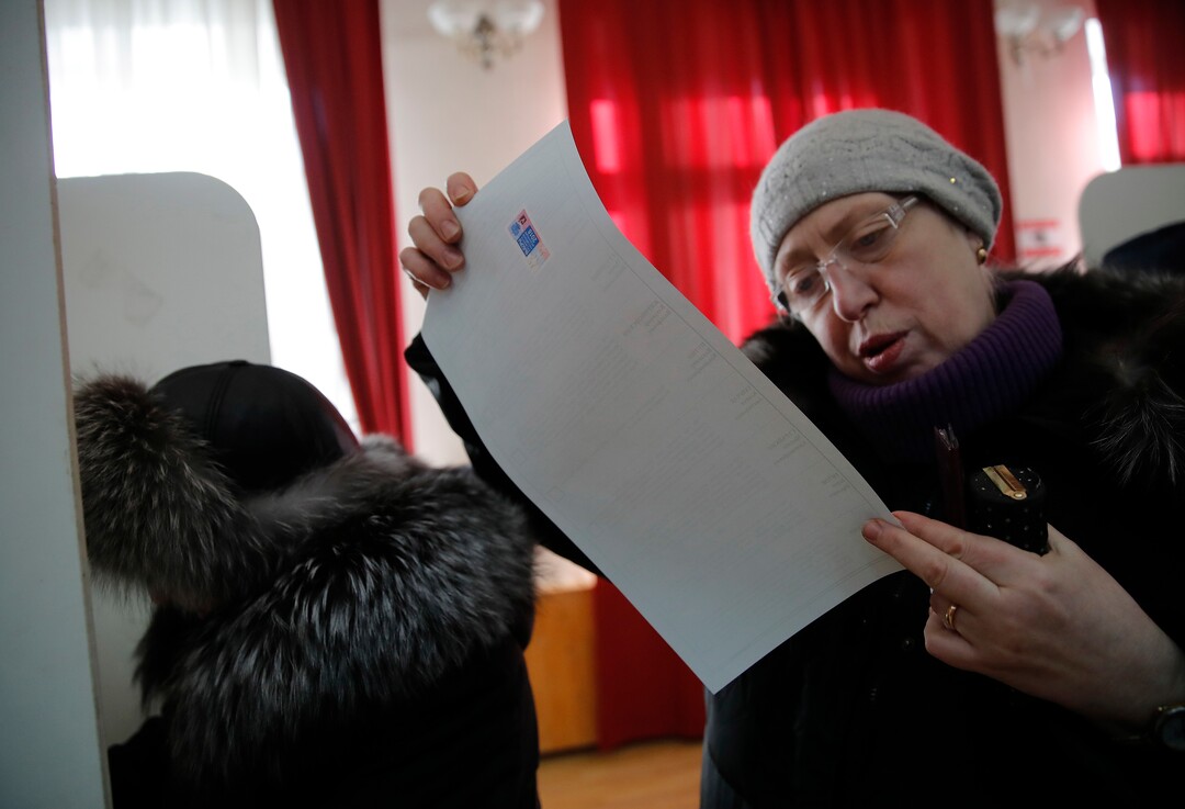 A woman studies her ballot paper as she prepares to cast a vote in the presidential election in Moscow, Russia, Sunday, March 18, 2018. Russians are voting in a presidential election in which Vladimir Putin is seeking a fourth term in the Kremlin. (AP Photo/Pavel Golovkin)