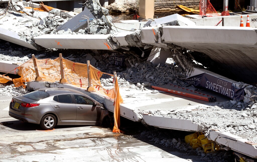 (Wilfredo Lee | The Associated Press) Crushed cars are shown under a section of a collapsed pedestrian bridge, Friday, March 16, 2018 near Florida International University in the Miami area. The new pedestrian bridge that was under construction collapsed onto a busy Miami highway Thursday afternoon, crushing vehicles beneath massive slabs of concrete and steel, killing and injuring several people, authorities said.