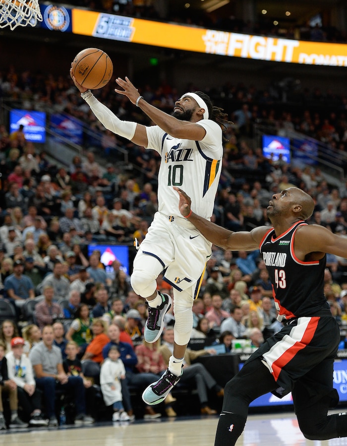(Francisco Kjolseth  |  The Salt Lake Tribune)  Utah Jazz guard Mike Conley (10) soars over Portland Trail Blazers forward Anthony Tolliver (43) as the Utah Jazz host the Portland Trailblazers in their NBA basketball game at Vivint Smart Home Arena in Salt Lake City on Wed. Oct. 16, 2019.