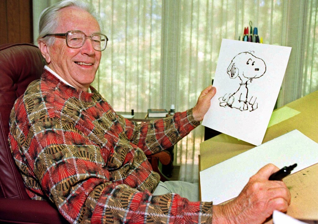 FILE - In this Feb. 12, 2000, file photo, cartoonist Charles Schulz displays a sketch of his beloved character "Snoopy" in his office in Santa Rosa, Calif. The home of “Peanuts” creator Schulz burned to the ground in the deadly California wildfires but his widow escaped, her stepson said Thursday, Oct. 12, 2017. Jean Schulz, 78, evacuated before flames engulfed her hillside home Monday and is staying with a daughter, Monte Schulz said. (AP Photo/Ben Margot, File)