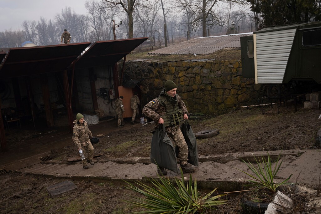 (Evgeniy Maloletka | AP) Ukrainian solders walk around an air defense base after an apparent Russian strike in Mariupol, Ukraine, Thursday, Feb. 24, 2022.