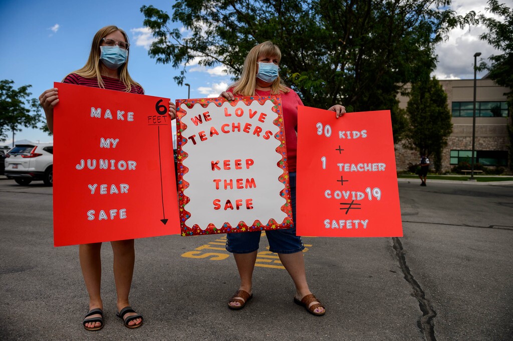 (Trent Nelson  |  The Salt Lake Tribune) Emily and Lucinda Webb join teachers and parents holding signs calling for a safe plan on reopening schools prior to a Jordan School District board meeting in Riverton on Tuesday, July 28, 2020.