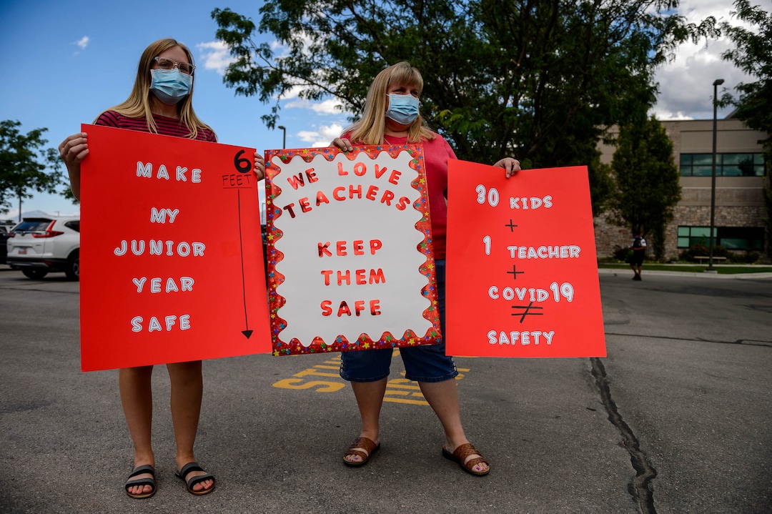 (Trent Nelson  |  The Salt Lake Tribune) Emily and Lucinda Webb join teachers and parents holding signs calling for a safe plan on reopening schools prior to a Jordan School District board meeting in Riverton on Tuesday, July 28, 2020.