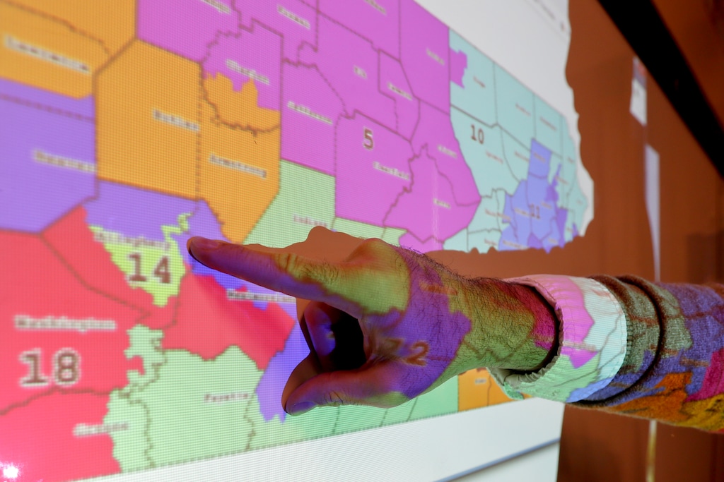 FILE- In this Nov. 16, 2018, file photo William Marx points out one of the districts that crossed four counties as an image of the old congressional districts of Pennsylvania are projected on a wall in the classroom where he teaches civics in Pittsburgh. In Pennsylvania, the Democratic-majority state Supreme Court redrew the congressional map for the 2018 elections after striking down the previous Republican-drawn version as an unconstitutional partisan gerrymander. (AP Photo/Keith Srakocic, File)