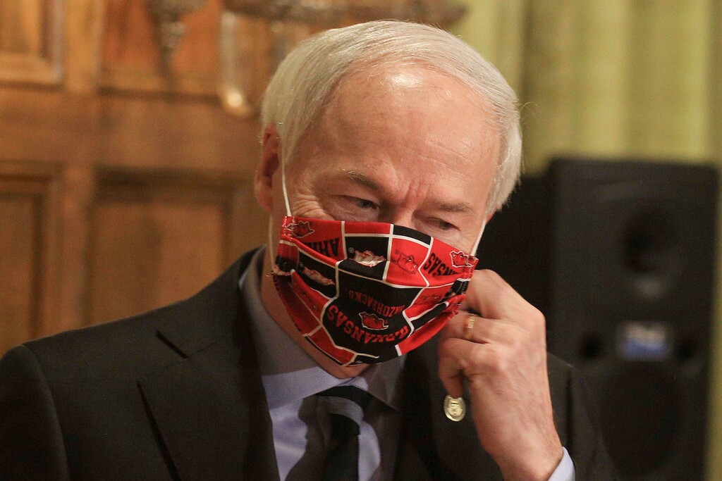 (Staton Breidenthal | Arkansas Democrat-Gazette via AP file photo)  Gov. Asa Hutchinson takes off his Arkansas Razorbacks mask as he arrives for a daily coronavirus briefing at the state Capitol in Little Rock, Ark. on April 27, 2020.