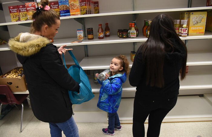 (Francisco Kjolseth  |  The Salt Lake Tribune)  Jodi Burnett, left, picks out food from the pantry with her daughters October, 5, and Isabella Flores, 16, as Salt Lake City's Winter De-Stressor Festival at the Horizonte Instruction and Training Center on Saturday, Dec. 15, 2018, to help families identify and locate services or programs open to youth during between Christmas and New Years.