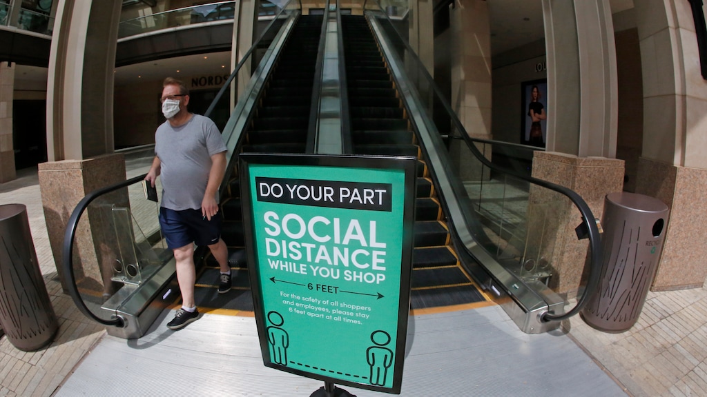 A man walks past a "Social Distance" sign at City Creek Center Wednesday, May 6, 2020, in Salt Lake City. City Creek Center reopened today. Several major Utah malls have reopened after Utah leaders moved the state's COVID-19 risk level from high to moderate. (AP Photo/Rick Bowmer)