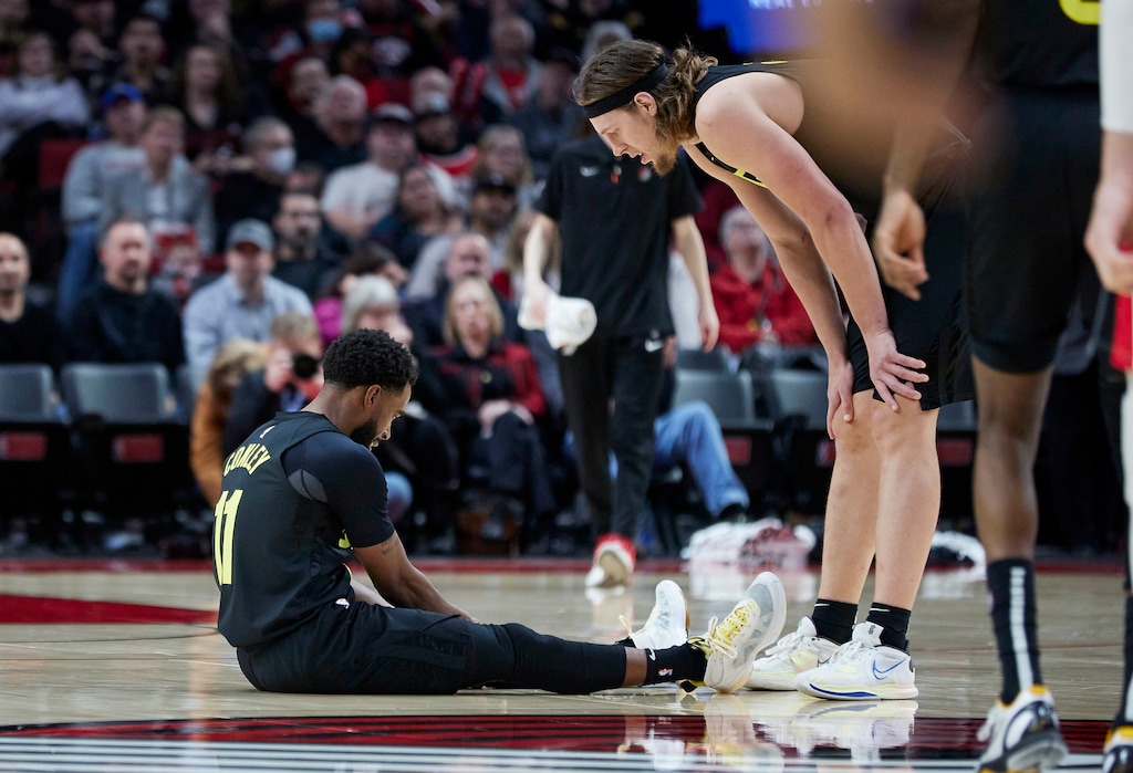 Utah Jazz forward Kelly Olynyk, right, talks to guard Mike Conley, who sits on the court after being injured during the second half of the team's NBA basketball game against the Portland Trail Blazers in Portland, Ore., Saturday, Nov. 19, 2022. (AP Photo/Craig Mitchelldyer)